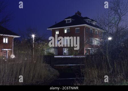 Maison sur le canal et des lampes lumineuses lors d'une soirée d'automne brumeuse. Automne. Banque D'Images