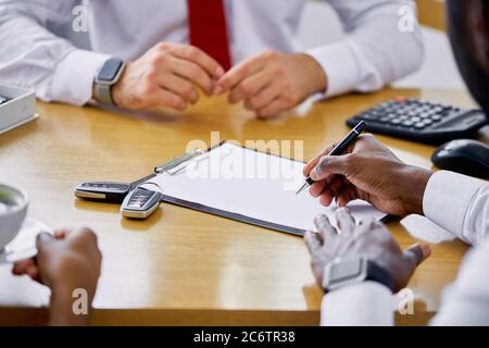 un vendeur professionnel caucasien affable montre le document aux clients, parle des avantages de faire entrer la voiture dans leur concessionnaire Banque D'Images