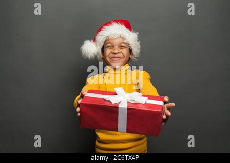 Joyeux père Noël africain américain tenant une boîte de Noël rouge avec un ruban blanc soyeux sur fond noir Banque D'Images