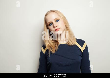 Adolescente avec maquillage portant une manches longues bleues sur fond blanc Banque D'Images