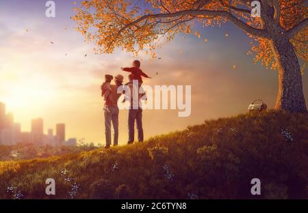 Bonne famille au coucher du soleil. Père, mère et deux enfants filles s'amusant et jouant sur la nature automnale. L'enfant est assis sur les épaules du salut Banque D'Images