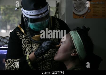 Les maquillages qui utilisent des équipements de protection individuelle font du maquillage pour la mariée et le marié avant la séance de photo avant mariage dans l'un des studios de photo Bekasi, dimanche (07/12/2020). Au moment d'une pandémie comme celle-ci est certainement un moment très difficile pour la profession d'un maquilleur. En plus des outils de maquillage qui touchent directement le visage du client, la propreté et la transmission ont également tendance à être vulnérables en raison de la distance et du contact physique qui est proche d'autres chiffres. (Photo de Kuncoro Widyo Rumpoko/Pacific Press) Banque D'Images