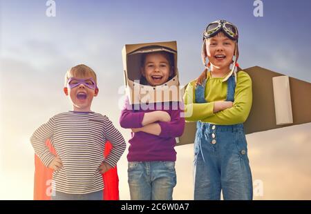 Les enfants en costumes d'astronaute, de pilote et de super héros rient, jouent et rêvent. Portrait des enfants amusants sur la nature. Jeux pour amis en famille outdoo Banque D'Images