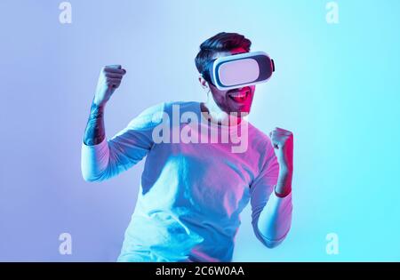 Gagner dans le jeu virtuel. Un gars heureux en lunettes vr se réjouit de la victoire Banque D'Images