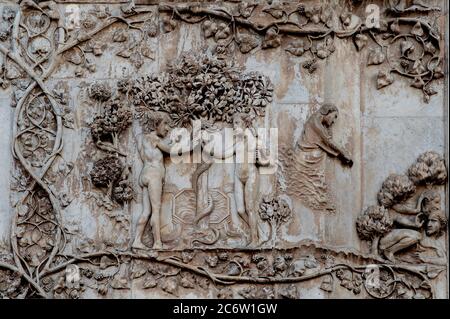 Adam et Ève coulent en se cachant du jugement de Dieu après avoir défié son avertissement de ne pas manger le fruit interdit de l'arbre de la connaissance du bien et du mal. bas-relief en marbre sur la façade ouest de la cathédrale d'Orvieto, Ombrie, Italie, attribué à Lorenzo Maitani (c. 1275 - 1330), qui a conçu la façade gothique tardive de la cathédrale. Maitani aurait eu une contribution directe en tant que sculpteur sur deux panneaux couvrant deux des quatre pilastres inférieurs de la façade : un panneau de Maitani représente des scènes de la Bible hébraïque / ancien Testament, y compris la scène dans cette image. Banque D'Images