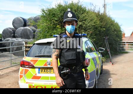 Un policier portant un masque facial à la ferme de Rook Row à Mathon, près de Malvern, dans le Herefordshire, où 73 cas positifs de coronavirus ont été confirmés. Banque D'Images