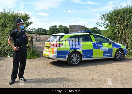 Un policier portant un masque facial à la ferme de Rook Row à Mathon, près de Malvern, dans le Herefordshire, où 73 cas positifs de coronavirus ont été confirmés. Banque D'Images