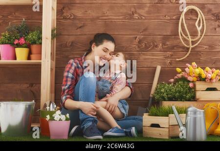 Une petite fille adorable aide sa mère à s'occuper des plantes. Mère et sa fille se sont engagées dans le jardinage dans la cour. Concept de printemps, nature et soins. Banque D'Images