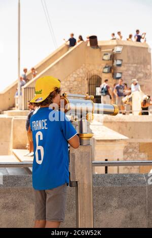 Jeune garçon utilisant un télescope à la Basilique notre-Dame de la Garde à Marseille France Banque D'Images