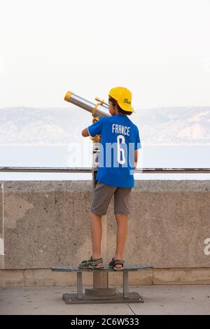 Jeune garçon utilisant un télescope à la Basilique notre-Dame de la Garde à Marseille France Banque D'Images