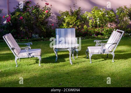 Trois chaises de jardin entourent une table en fer forgé dans le jardin d'un hôtel sud-africain. Banque D'Images