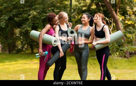 Concept de mode de vie sain. Jeunes dames joyeuses qui parlent en attendant leur entraînement de yoga en plein air Banque D'Images