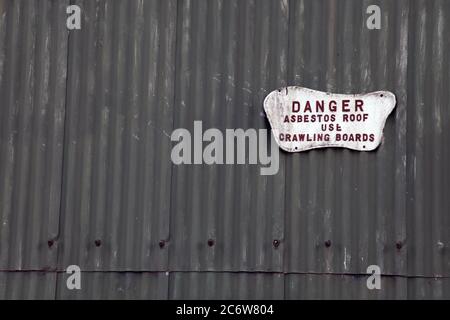 Danger panneau de toit en amiante fixé sur le côté de la grange agricole en métal ondulé avec espace de copie, printemps 2020 Banque D'Images