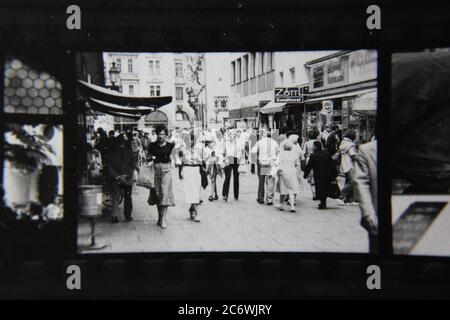 Belle photo de style de vie noir et blanc vintage des années 70 des personnes qui marchent autour d'un marché de rue extérieur. Banque D'Images