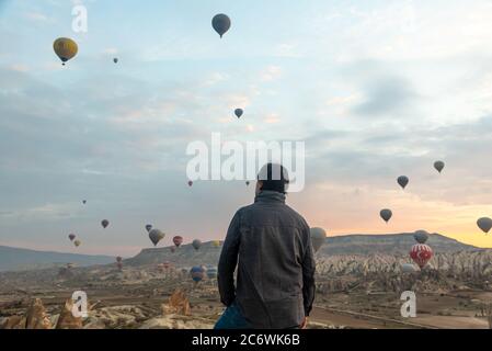 24 février 2018: Homme profitant de la vue sur la vallée avec de merveilleux ballons voler au-dessus de la vallée de Cappadoce. Göreme, Cappadoce, Turquie Banque D'Images