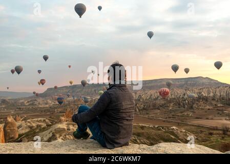 24 février 2018: Homme profitant de la vue sur la vallée avec de merveilleux ballons voler au-dessus de la vallée de Cappadoce. Göreme, Cappadoce, Turquie Banque D'Images