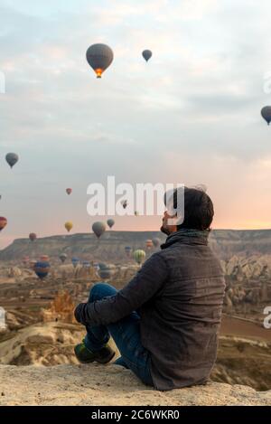 24 février 2018: Homme profitant de la vue sur la vallée avec de merveilleux ballons voler au-dessus de la vallée de Cappadoce. Göreme, Cappadoce, Turquie Banque D'Images
