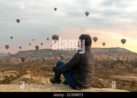 24 février 2018: Homme profitant de la vue sur la vallée avec de merveilleux ballons voler au-dessus de la vallée de Cappadoce. Göreme, Cappadoce, Turquie Banque D'Images