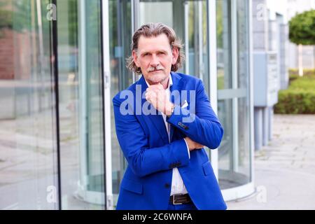 beau homme d'affaires dans ses années 50 en costume bleu debout à l'extérieur Banque D'Images