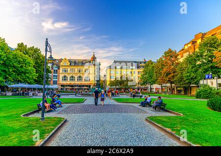 Koblenz, Allemagne, 23 août 2019 : place Gorresplatz avec anciens bâtiments, fontaine de la colonne d'histoire, pelouse verte et personnes assises sur des bancs dans le centre-ville historique, État de Rhénanie-Palatinat Banque D'Images