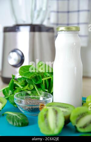 Ingrédients pour un smoothie vert. Fond turquoise de banane, épinards, graines de chia, lait de coco dans un pot en verre, avocat, raisin. Détox, smoothie r Banque D'Images
