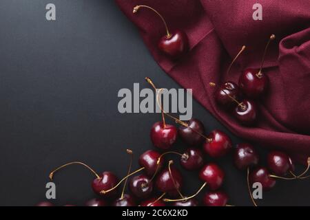 Fond de cerisier. Cerises sur une vue de dessus noire. Fond élégant et riche en cerisier. Fond de Bourgogne avec récolte estivale de baies de cerises. Copier l'espace Banque D'Images