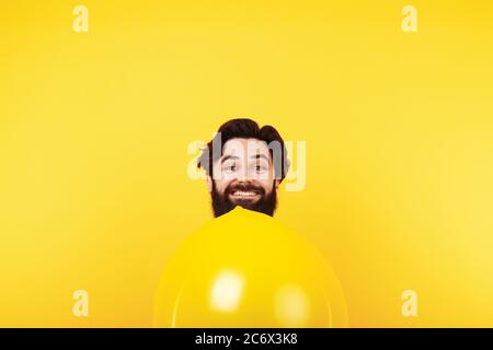 homme souriant avec ballon jaune gonflable, homme de vacances sur fond clair Banque D'Images