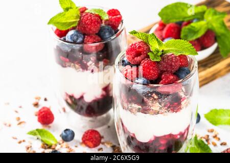 Parfait avec du granola, de la confiture et des baies fraîches dans le pot en verre. Banque D'Images