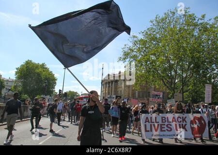 Un manifestant tient un drapeau noir pendant la manifestation.tous les manifestants de Black Lives Matter ont défilé de Hyde Park à la place du Parlement. Le mouvement dirigé par les jeunes organise des manifestations chaque dimanche pour lutter pour l'égalité raciale et la justice pour tous les Noirs au Royaume-Uni. Banque D'Images