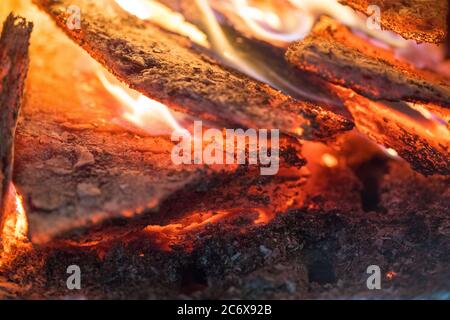 La flamme incinérée le bois de chauffage et le transforme en cendres, en gros plan, peu profonde profondeur de champ. Blaze dans un grand poêle. Nature texture du feu. La flamme de Banque D'Images