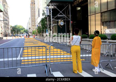 Mère et fille portant un stand jaune devant la peinture murale Black Lives Matter peinte sur la 5e avenue directement devant la Trump Tower, Manhattan, New York City, USA le 12 juillet 2020 Banque D'Images