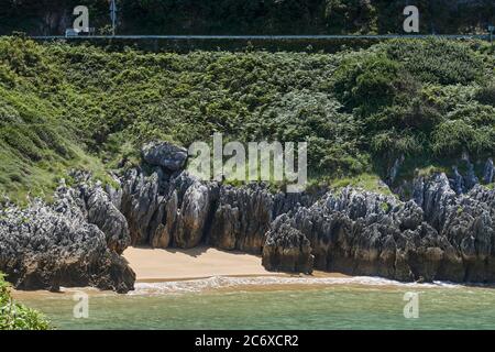 Petite plage vide entourée de rochers et de grandes pierres avec végétation dans la ville d'Islares de Cantabria, Espagne, Europe Banque D'Images