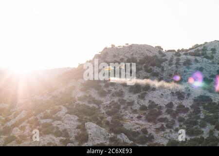 Hélicoptère de feux de jets d'eau sur les montagnes au coucher du soleil. Pompier concept et extinction des incendies. Banque D'Images