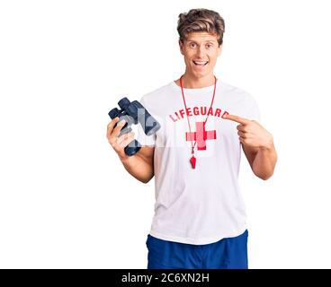 Jeune homme beau portant un t-shirt de sauvetage avec des jumelles souriant heureux pointant avec la main et le doigt Banque D'Images