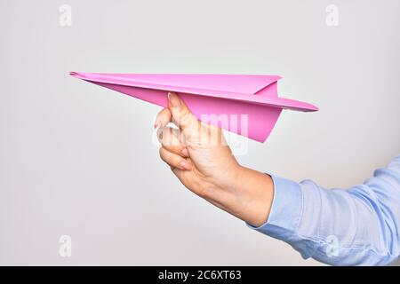 Main de la jeune femme caucasienne tenant un avion en papier sur fond blanc isolé Banque D'Images