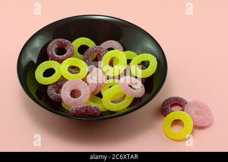 Croque-les de bonbon à la limonade aigre dans un bol à collation noir sur fond rose Banque D'Images