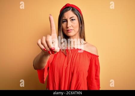 Jeune belle femme coloré style d'été sur fond jaune isolé pointant avec le doigt vers le haut et expression de colère, ne montrant aucun geste Banque D'Images