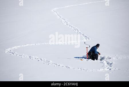 Un homme d'âge moyen pêchant sur glace à Winter, Finlande Banque D'Images