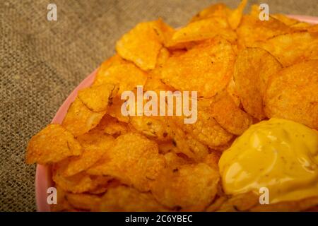 Croustilles sur un plateau rond et une casserole avec sauce au fromage. Gros plan Banque D'Images