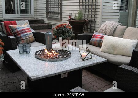 Des sièges extérieurs autour d'une table de cheminée à gaz à l'automne sur un patio Banque D'Images