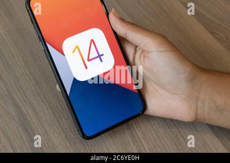 Personne tenant un iPhone avec le logo iOS 14, aples le plus récent logiciel d'exploitation. Banque D'Images