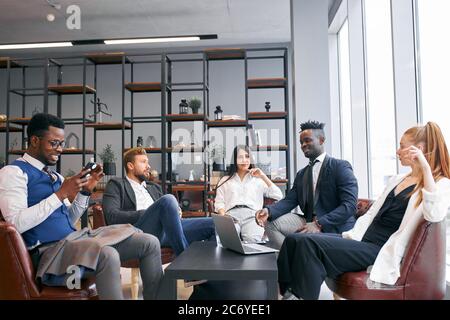 Un groupe de partenaires d'affaires interprofessionnels discute de l'avenir réussi dans le bureau moderne, portant des vêtements formels Banque D'Images