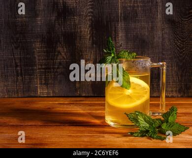 Tasse de thé vert avec citron et menthe sur planche à découper en bois Banque D'Images