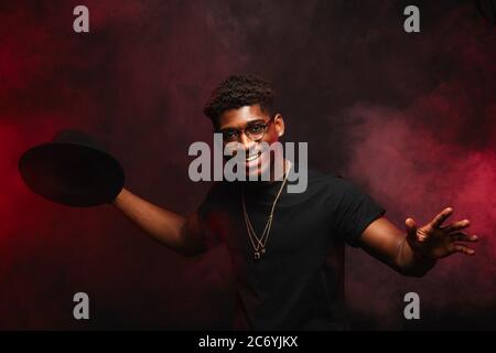 Portrait d'un jeune DJ africain ou musicien de jazz en chapeau créatif en t-shirt noir sur fond sombre Banque D'Images