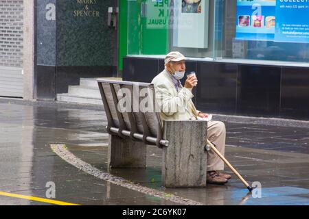 8 juillet 2020 un homme âgé avec un masque se détend avec une tasse de café chaud à l'extérieur du magasin Marks and Spencer de Fargate, au centre de Sheffield City Banque D'Images