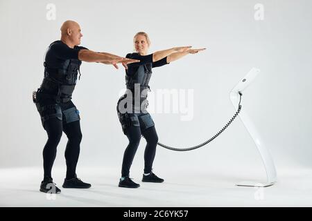 jeunes gens de fitness avec les bras devant eux faisant des squats d'entraînement. traitement de squat. photo pleine longueur. Banque D'Images