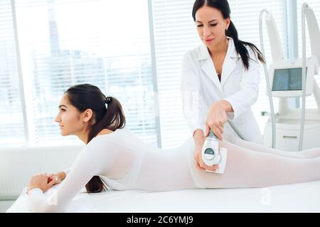 Gros plan du thérapeute esthéticienne massage GPL permet de jeune femme en costume blanc transparent, située à Spa de beauté clinique. Se concentrer sur les mains Banque D'Images