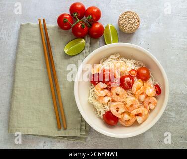 Bol de nouilles shirataki avec crevettes, tomates et oignons verts en gros plan. Banque D'Images