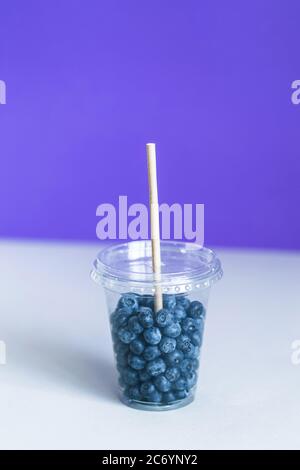 Bleuet dans la tasse en plastique smoothie avec une paille en papier Banque D'Images