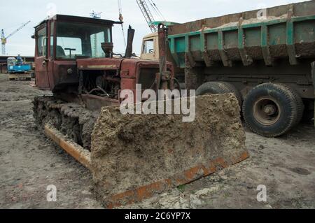 Le bulldozer sale de creusement tourne de l'argile pour des briques dans une petite usine de briques de travail rural. Dans un parking Banque D'Images